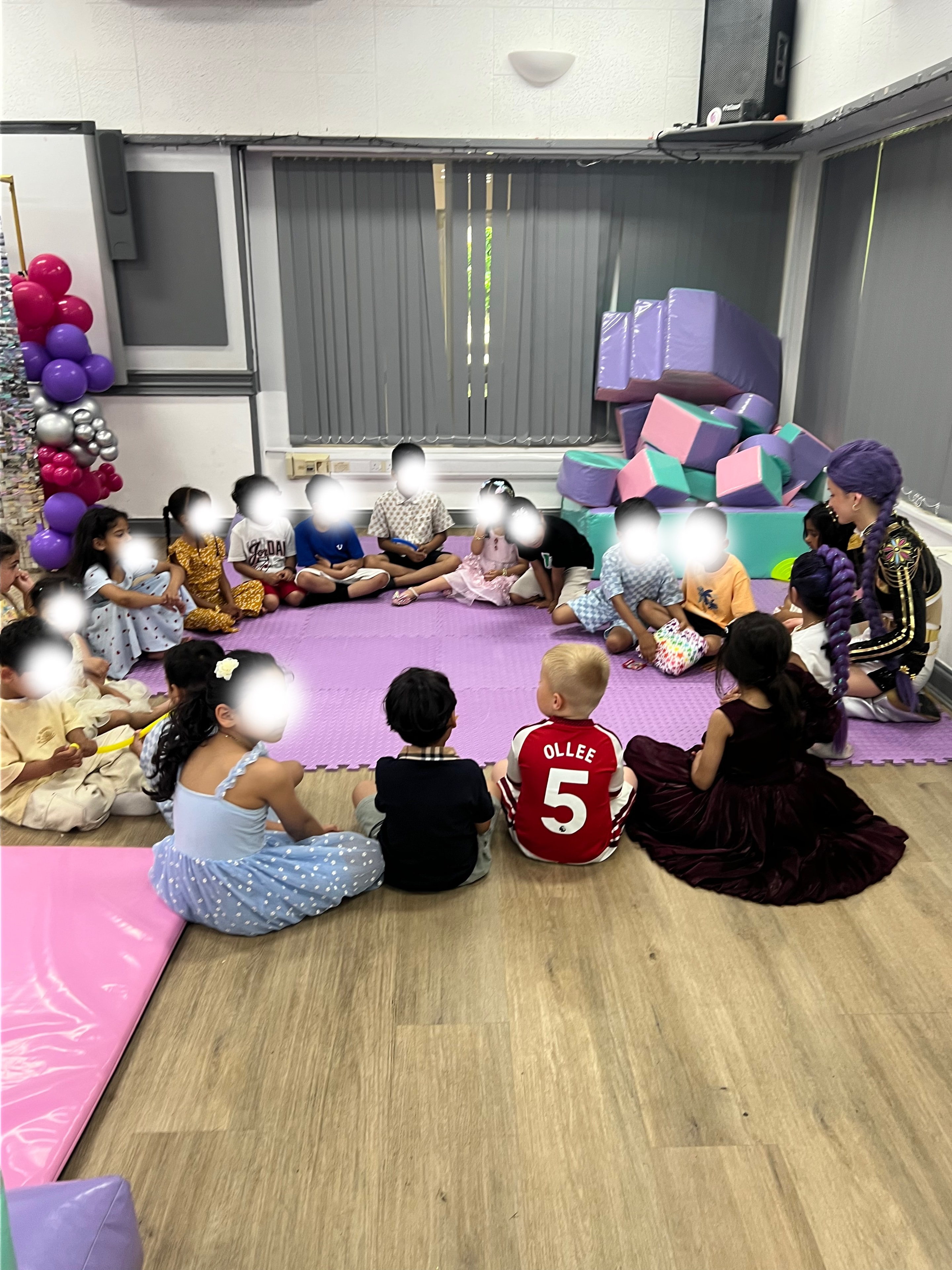 Children sitting in circle with character at indoor party